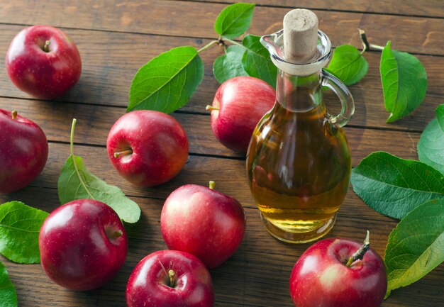 Ripe apples and apple cider vinegar in glass bottle on wooden table. Top view.