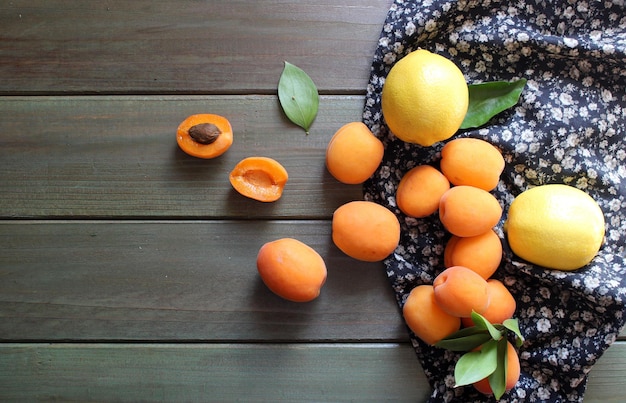 Photo ripe apricots and apricot leaves on the wooden background