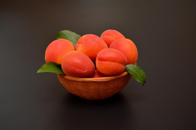 Ripe apricots in a basket on a black background