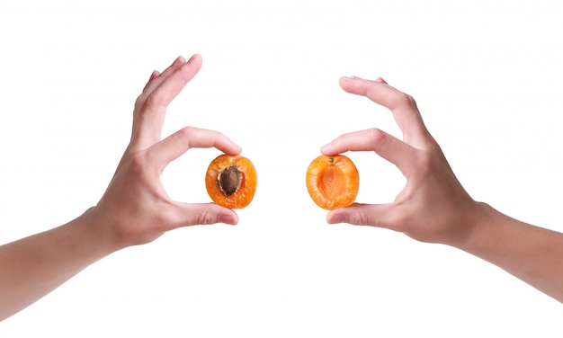 Ripe apricots in a hand on a white wall