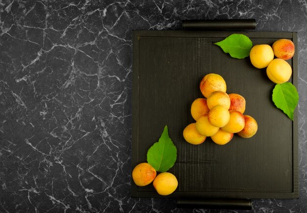 Ripe apricots lying on a black tray