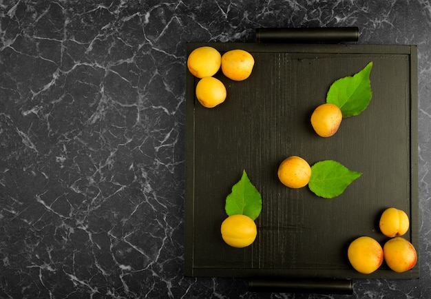 Ripe apricots lying on a black tray