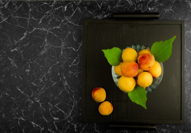 Ripe apricots lying on a black tray