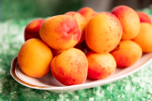 Ripe apricots in a plate on a green background