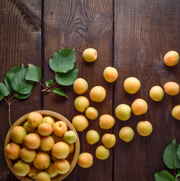 Ripe apricots scattered on a brown wooden table