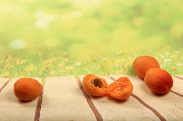 Ripe apricots on wooden board, green summer background, place for text