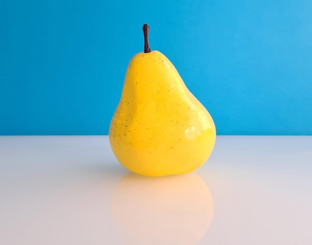 Ripe beautiful yellow artificial pear on blue background