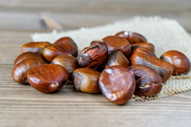 Ripe big chestnuts on the wooden background closeup