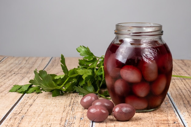 Ripe black olives with a bone and parsley on a wooden background.