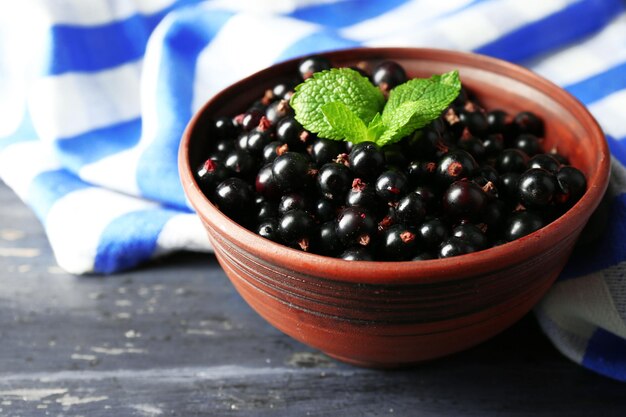 Foto ribes nero maturo in ciotola su fondo di legno