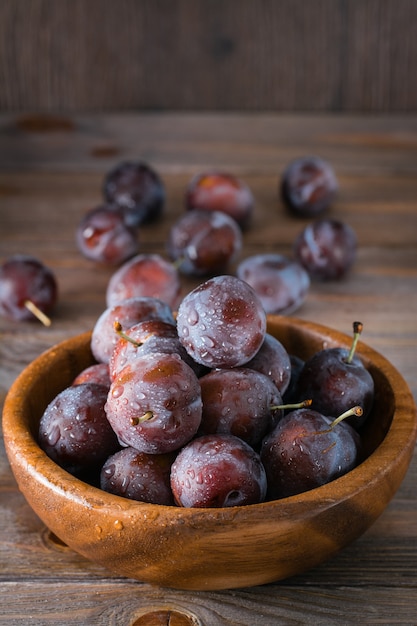 Ripe blue plum in a wooden plate on the table