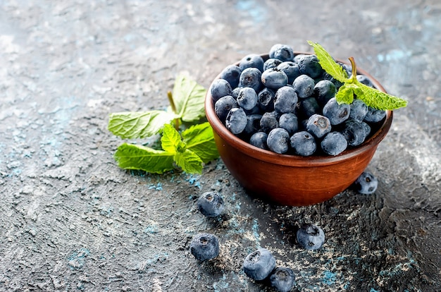 Ripe blueberries in bowl on a dark concrete background