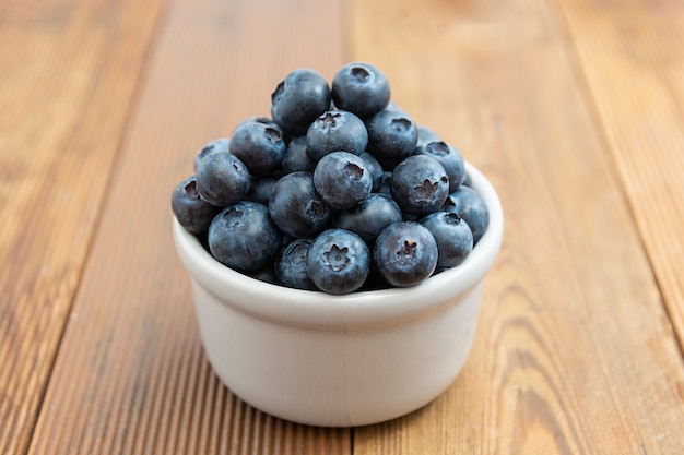 Ripe blueberries in the bowl on the wooden table, Fresh berries for breakfast.