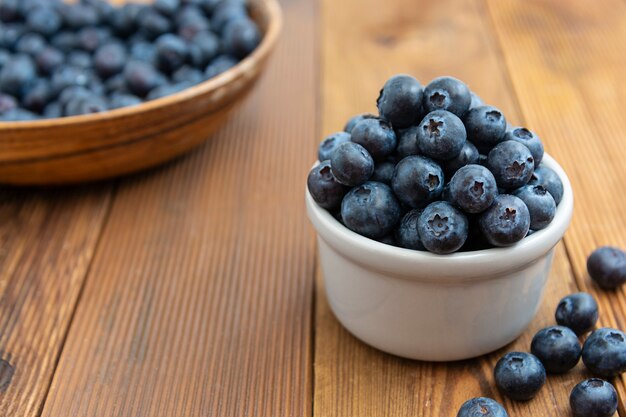 Ripe blueberries in the bowl on the wooden table, Fresh berries for breakfast.