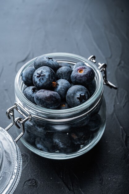 Ripe blueberries in a glass jar on dark wooden background