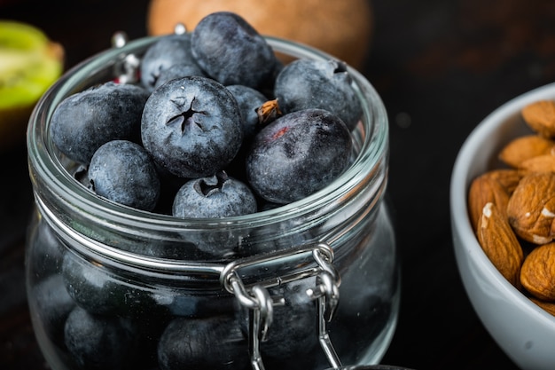 Ripe blueberry in glass jar on dark wooden background