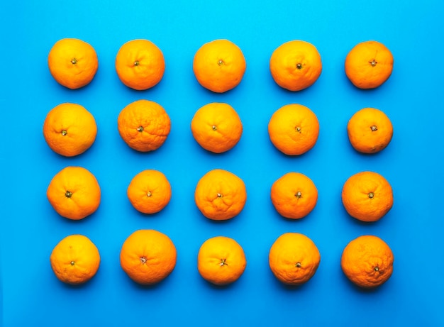 Ripe bright orange tangerines on blue background fruit pattern Top view