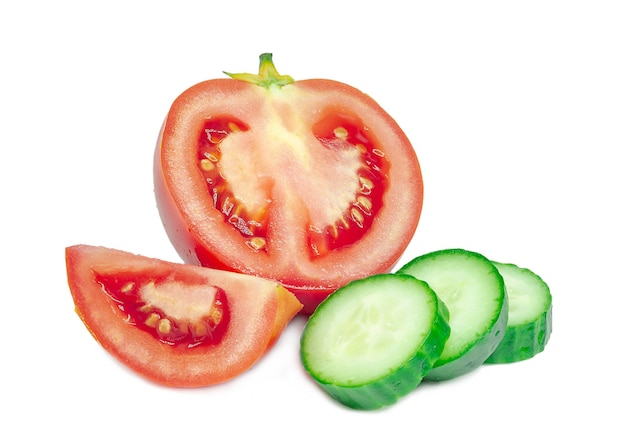 Pomodoro rosso affettato luminoso maturo con pochi pezzi rotondi di cetriolo verde dalla pelle liscia isolato su fondo bianco