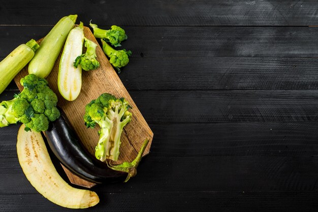 Ripe broccoli, eggplant and zucchini on wooden background. Copy space