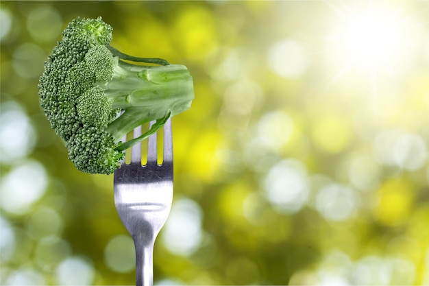 Ripe broccoli on fork over background