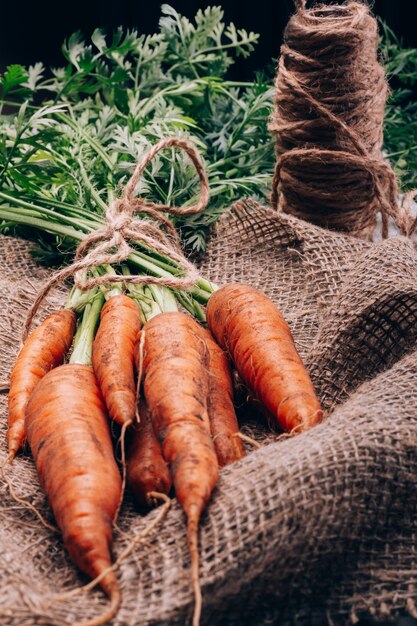 Photo ripe carrots with tops in burlap