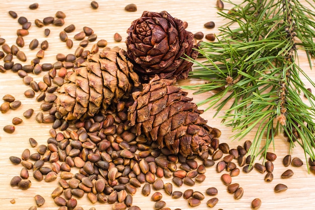 Photo ripe cedar cones, pine nuts and pine branches on a wooden table