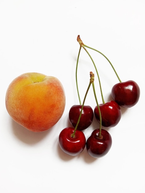 ripe cherries and peach on white background