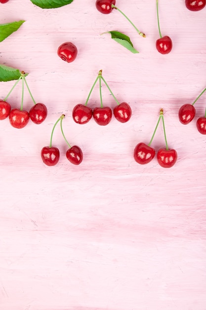 Ripe cherry berries and cherry leaf on pink background