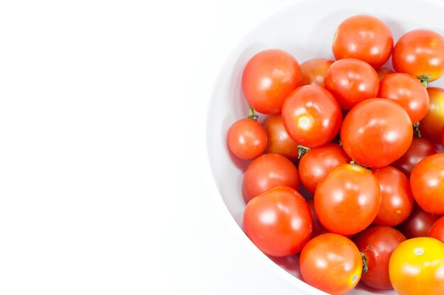 Ripe cherry tomatoes in a bowl on white background