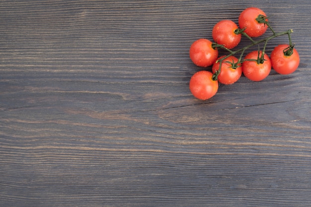 Ripe cherry tomatoes on a twig on a dark wooden background