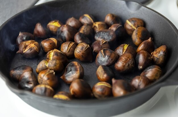 Ripe chestnuts are fried in a pan. the process of cooking chestnuts. Delicious delicacy. Photo