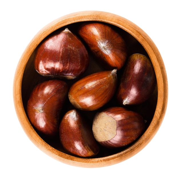 Ripe chestnuts in wooden bowl over white