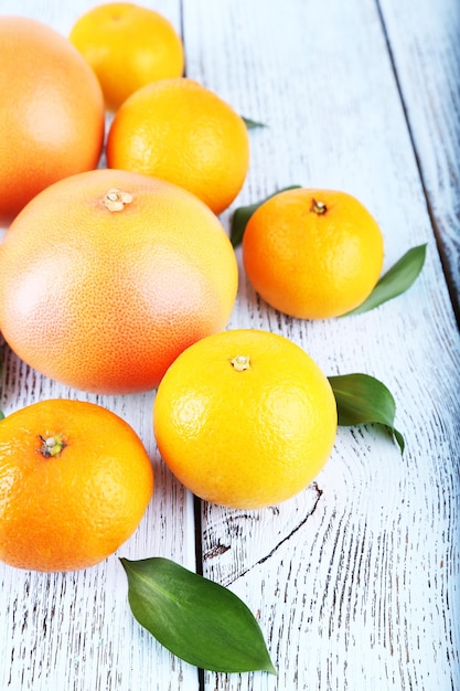 Ripe citrus with green leaves on wooden background