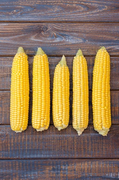 Ripe corn in a clay bowl on a dark brown wooden background