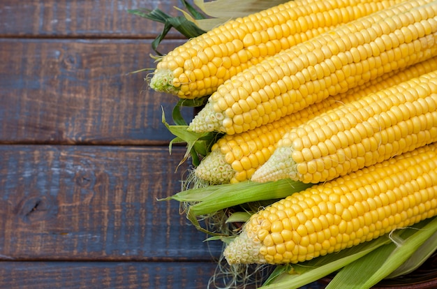 Ripe corn in a clay bowl on a dark brown wooden background.