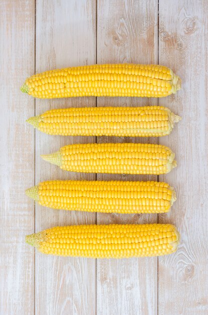 Ripe corn in a clay bowl on a light wooden background.