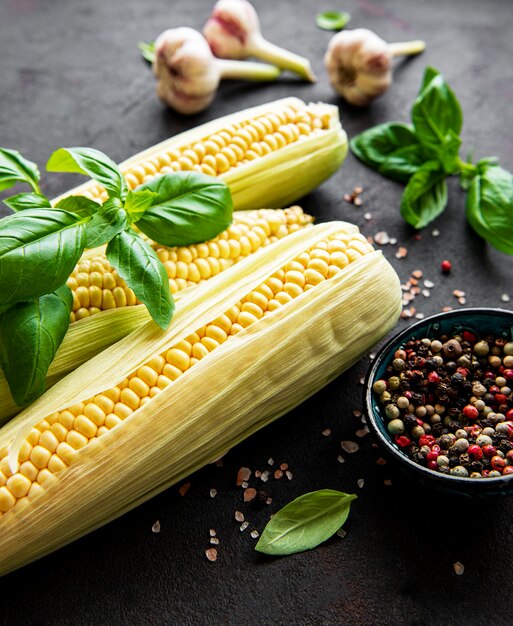 Ripe corn cob on black surface with spices