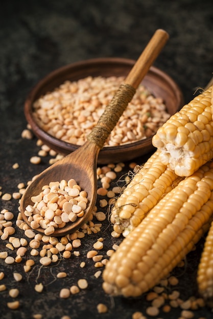 Ripe corn with pea seed on dark background.