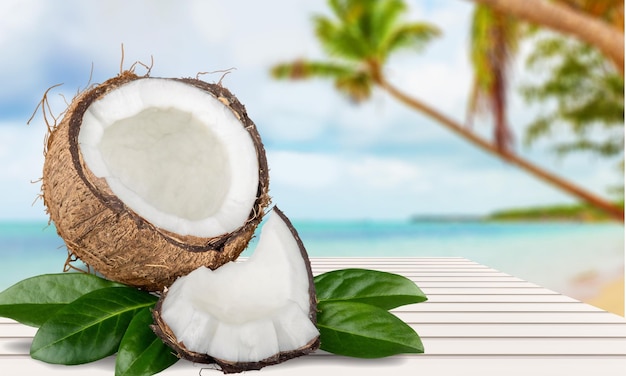 Ripe cut coconut and leaves on wooden table