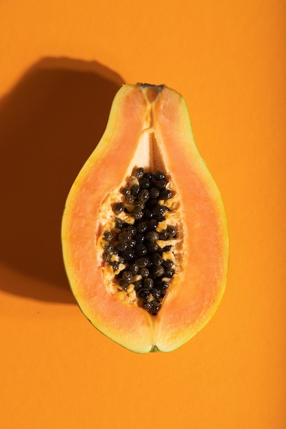 Papaya tagliata matura su sfondo arancione pastello vista dall'alto primo piano luce intensa