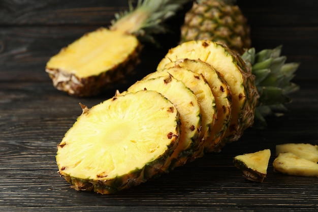 Ripe cutted pineapple on wooden background, close up