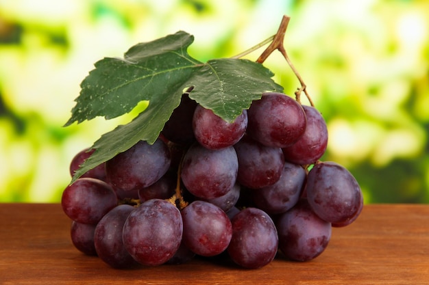 Ripe delicious grapes on table on bright background