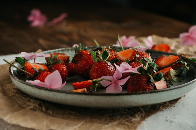 Ripe farm strawberries in a plate flowers on a white background fresh juicy strawberries