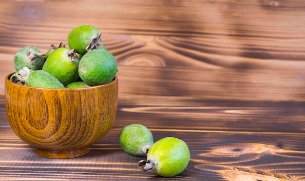 Ripe feijoa fruits in wooden bowl on wooden background