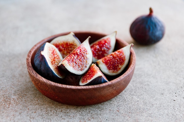 Ripe figs in a wooden small bowl on a table