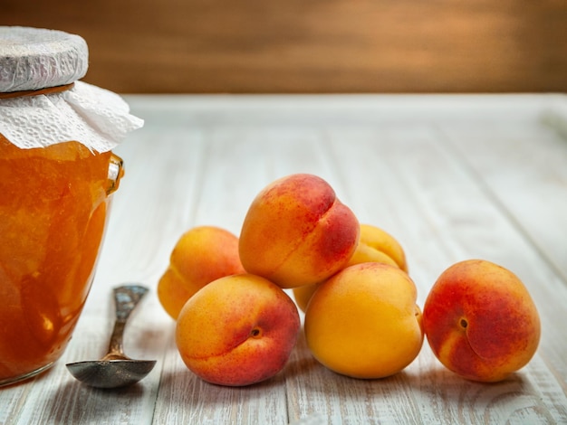 Ripe fresh apricots and apricot jam in a jar on a wooden background Selective focus healthy eating