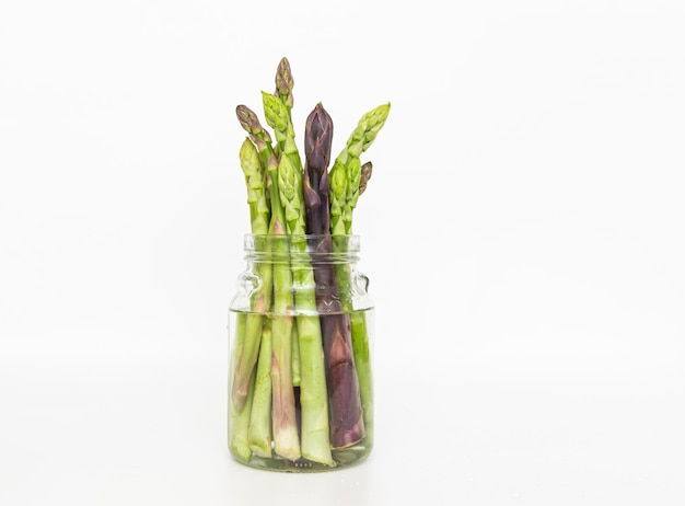 Foto arpelli di asparagi freschi maturi in vetro con acqua crispers asparagus bundle