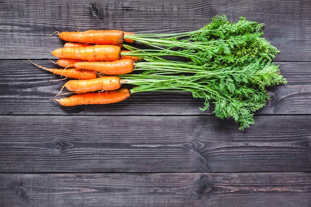 Ripe fresh carrots on a wooden background.