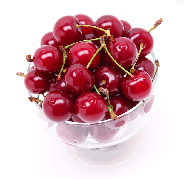 Ripe fresh cherry in the glass isolated on white background