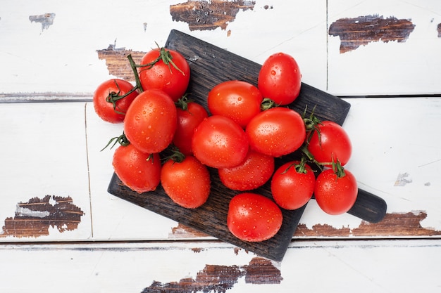 Ripe fresh cherry tomatoes on a branch on a wooden chopping Board. Wooden rustic table. Copy space.